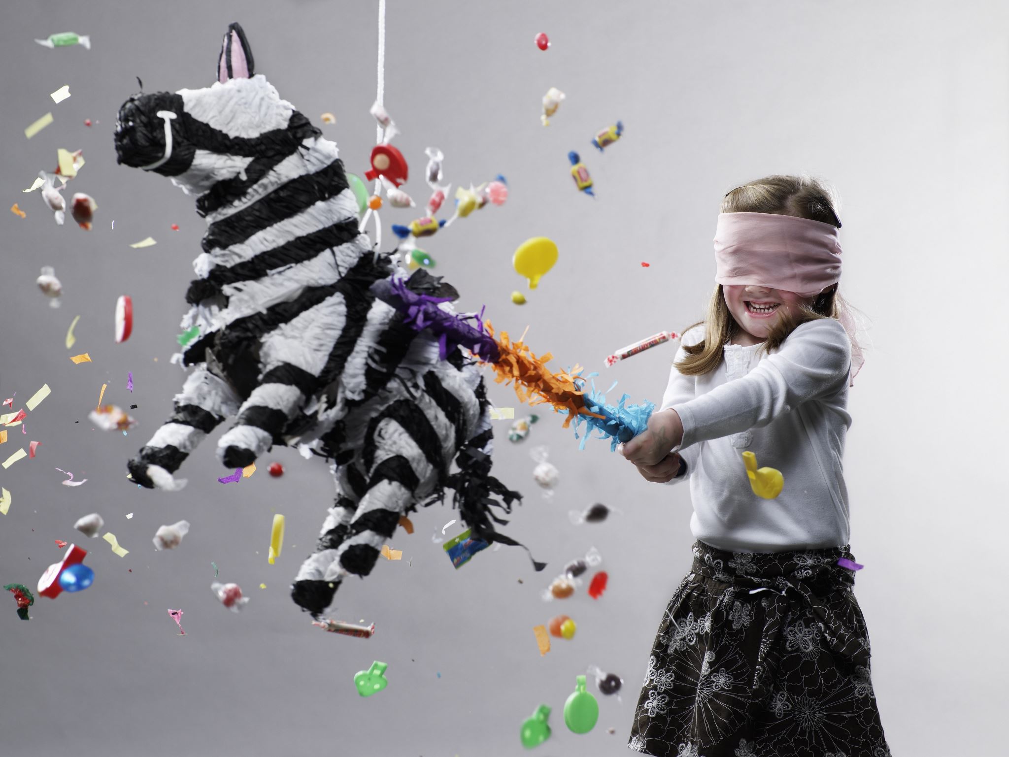 Young-girl-hitting-a-pinata-with-candy-flying